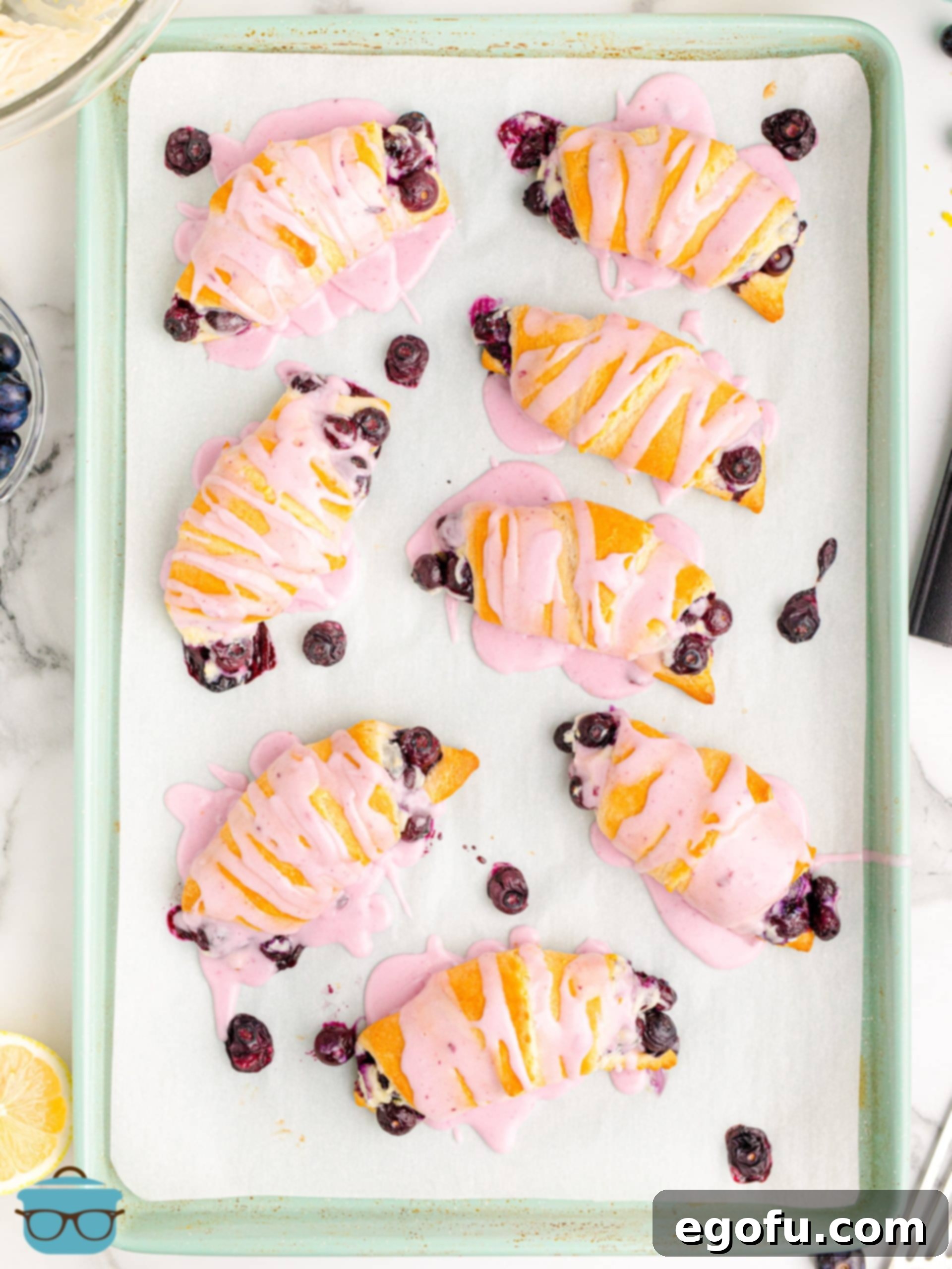 A top-down view of a baking sheet filled with golden-brown Blueberry Cheesecake Crescent Rolls, fresh out of the oven.