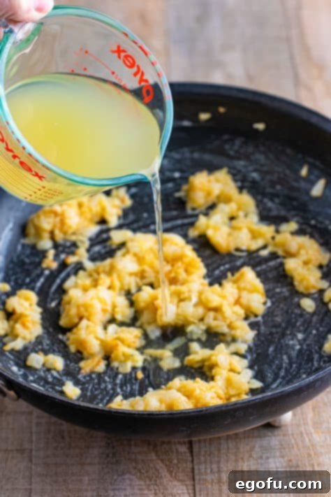 Chicken stock being added to saucepan.