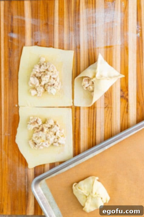 showing how to roll up the puff pastry over the chicken filling.