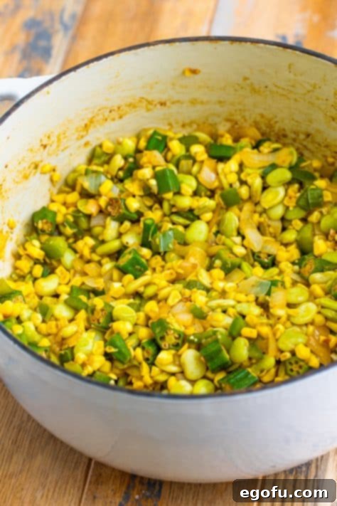 Cooked lima beans and fresh corn kernels added to the sautéed vegetables in a Dutch oven.