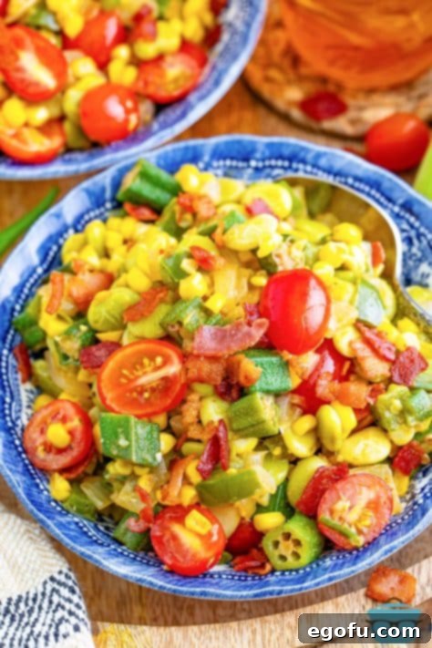 Looking down on a bowl of homemade Succotash with fresh grape tomatoes and crispy bacon garnish.