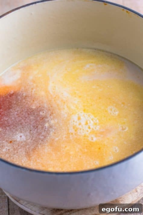 Wholesome Pasta O's 7 A Dutch oven with water, tomato sauce, half and half, sugar, and salt, melted butter, and garlic.