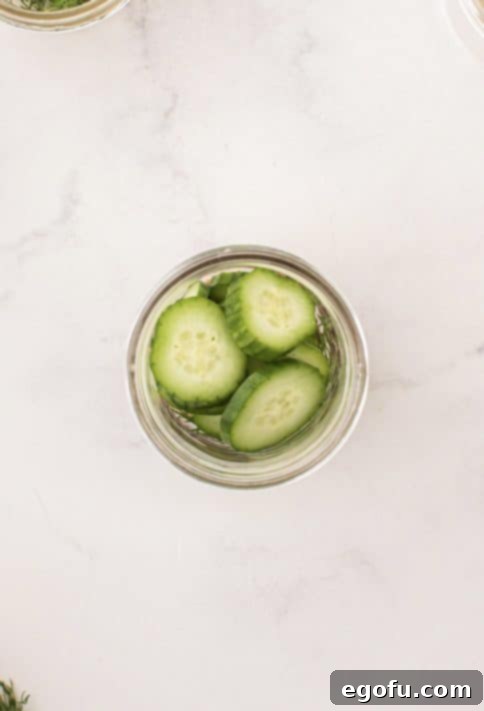 Sliced cucumbers are added to mason jar.