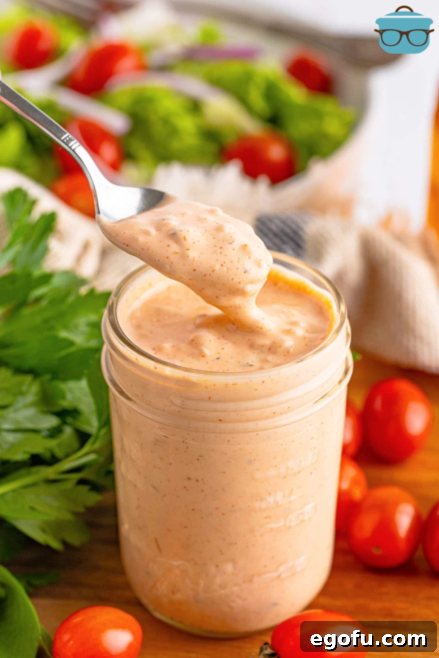 A spoon being dipped in and out of Thousand Island Dressing.