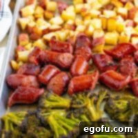 Close up looking at the broccolini, potatoes, and kielbasa for this sheet pan dinner.