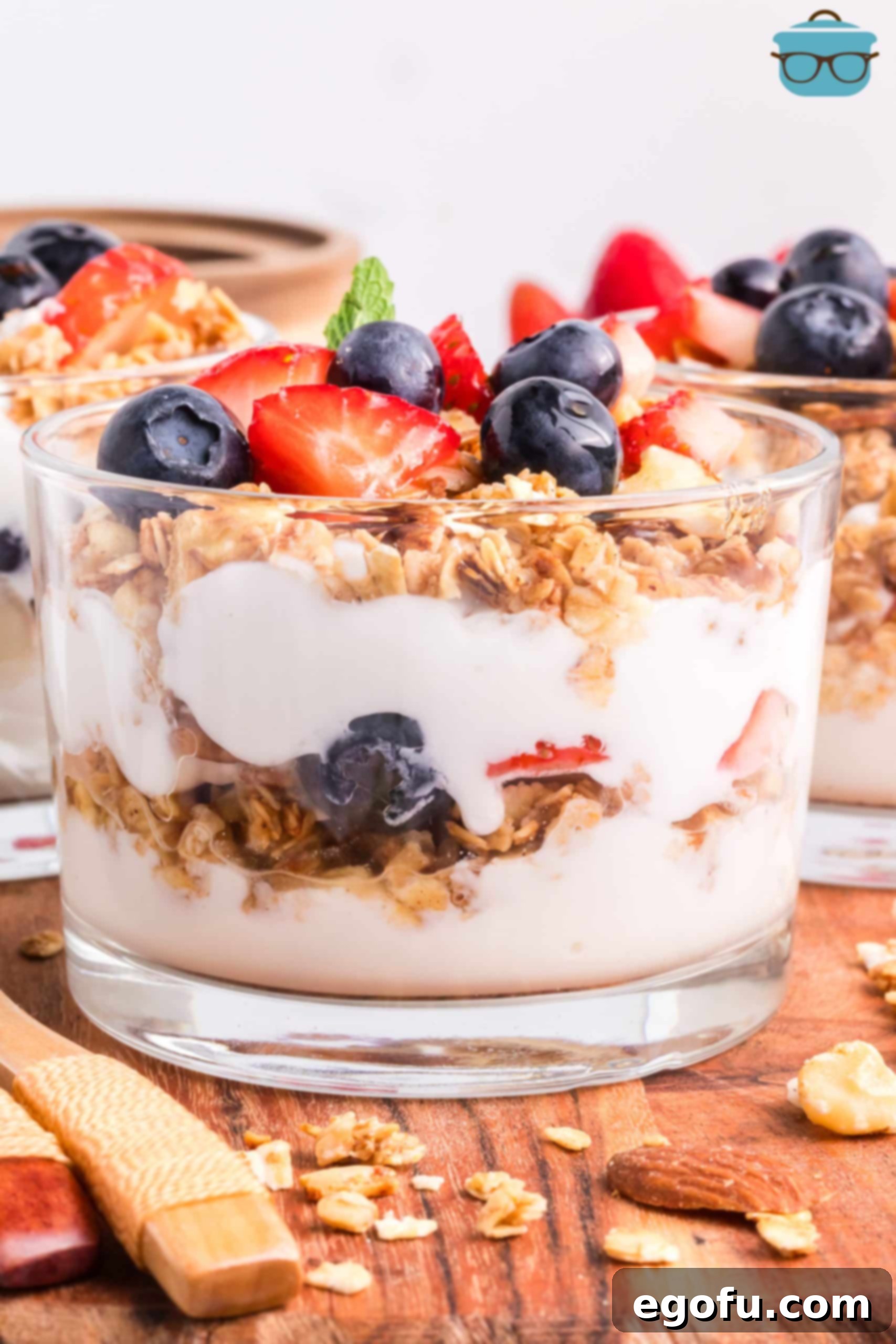 A layered Yogurt Parfait in a cup, showcasing visible layers of yogurt, berries, and golden-brown granola.