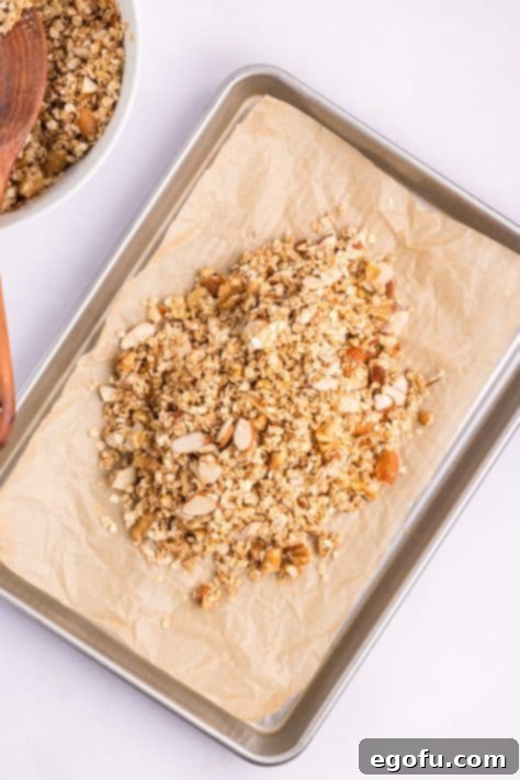Homemade granola on a parchment lined baking sheet, spread out.