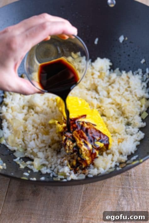 Cooked egg and soy sauce on top of rice in a wok.