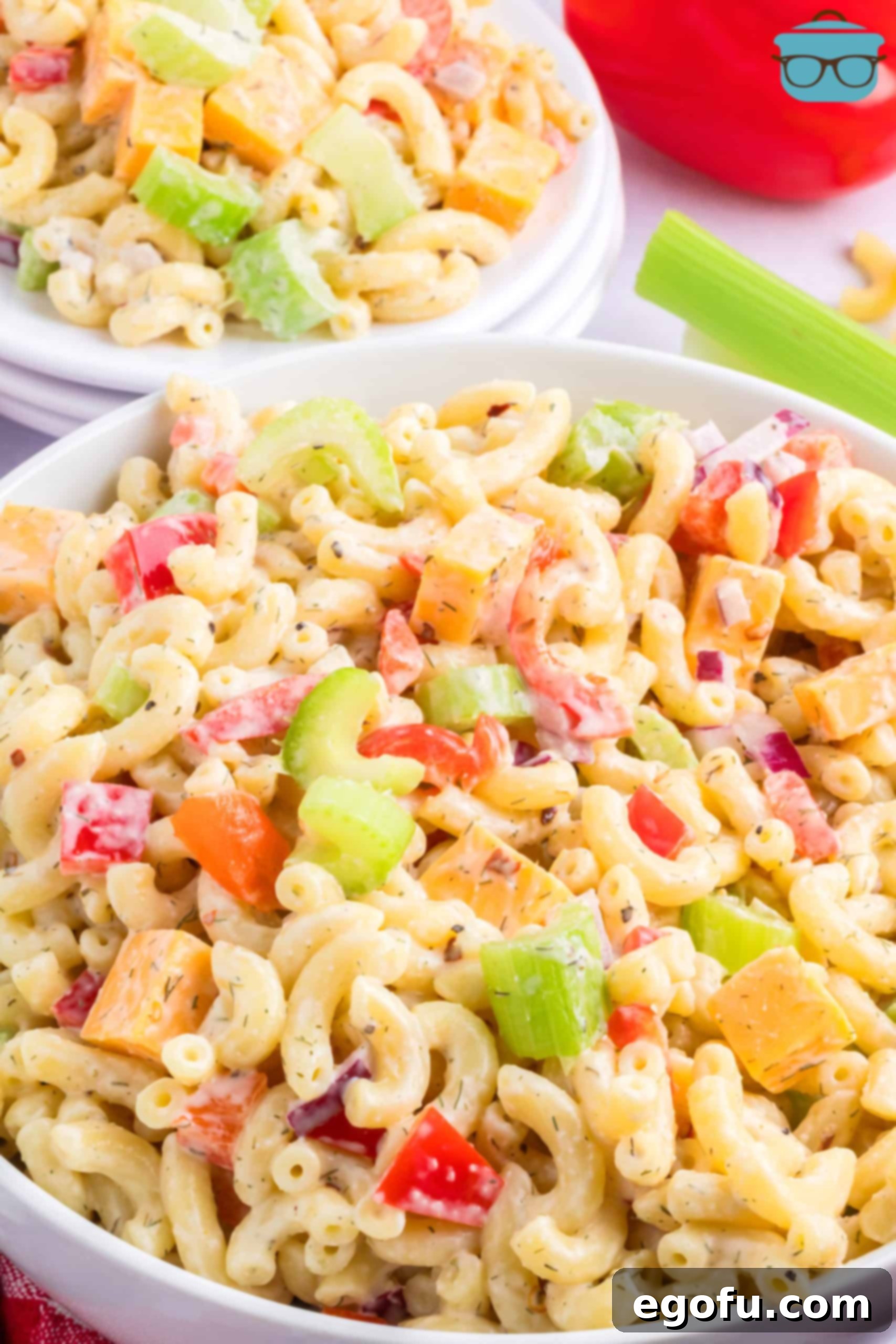 A close-up, top-down view of a generous serving of Amish Macaroni Salad, showcasing its vibrant ingredients and creamy texture.