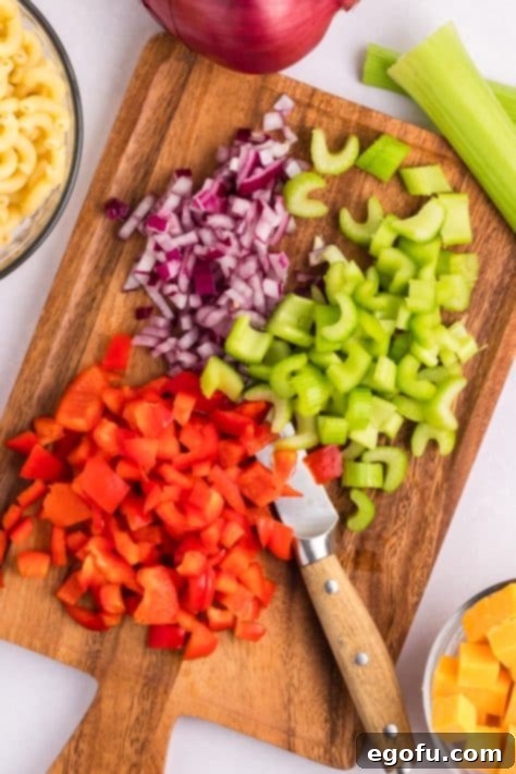 Red onion, celery, adn red bell pepper diced up on a cutting board.