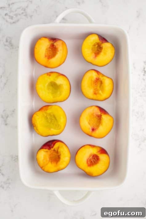 A baking dish with peaches cut in half and pits removed, ready for the next step.