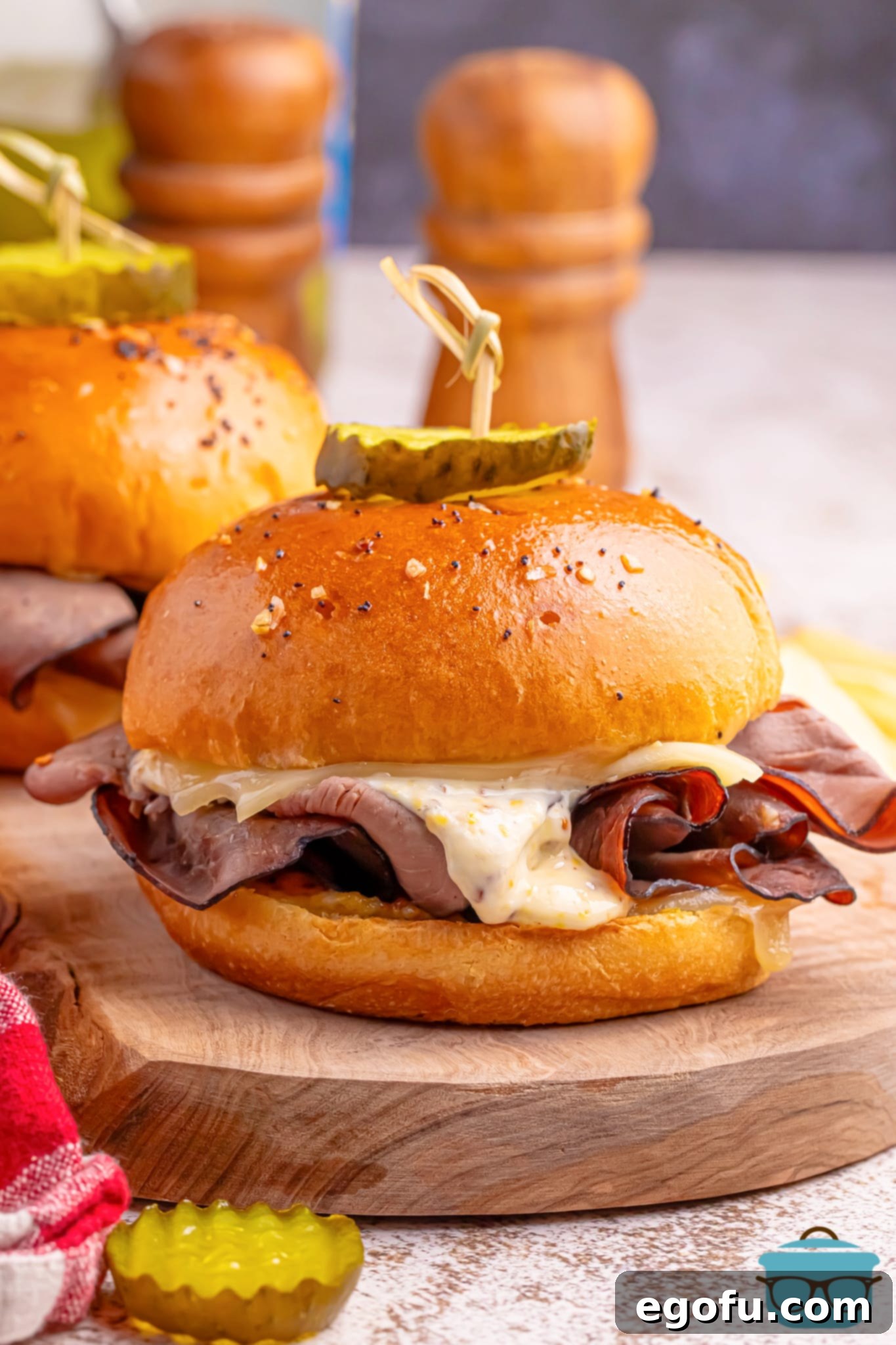 Ultimate Air Fryer Roast Beef Melts 2 Two Air Fryer Roast Beef Sandwiches on a wooden board, garnished with parsley.