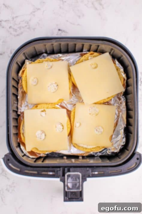 Ultimate Air Fryer Roast Beef Melts 10 Cheese on sandwich buns in the basket.