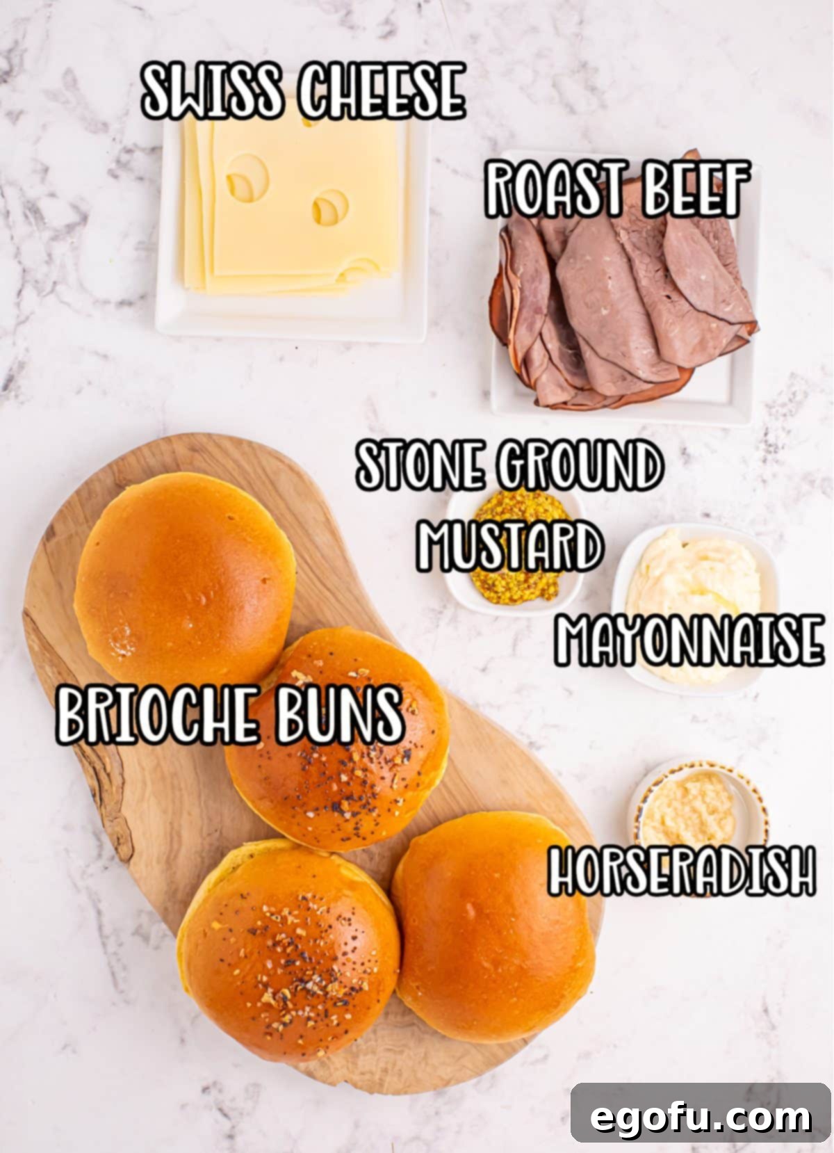 Ultimate Air Fryer Roast Beef Melts 3 A flat lay image showing brioche buns, roast beef, mayonnaise, stone ground mustard, horseradish, and Swiss cheese on a cutting board.