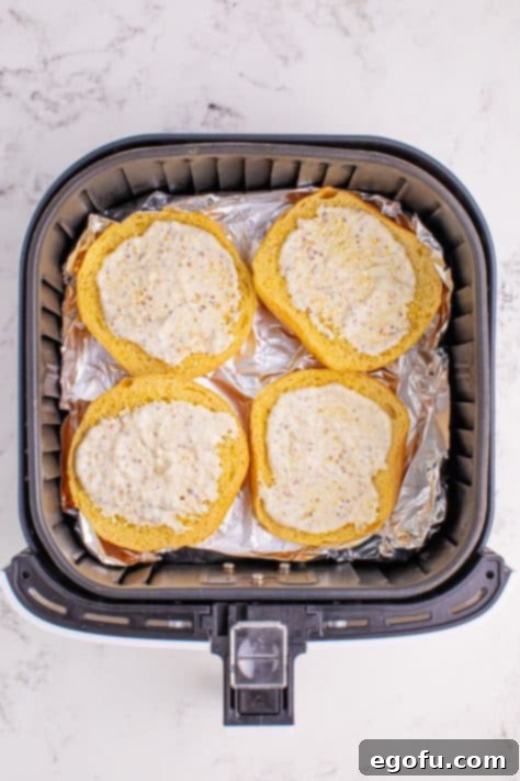 Ultimate Air Fryer Roast Beef Melts 9 Sauce spread on buns in an air fryer basket.