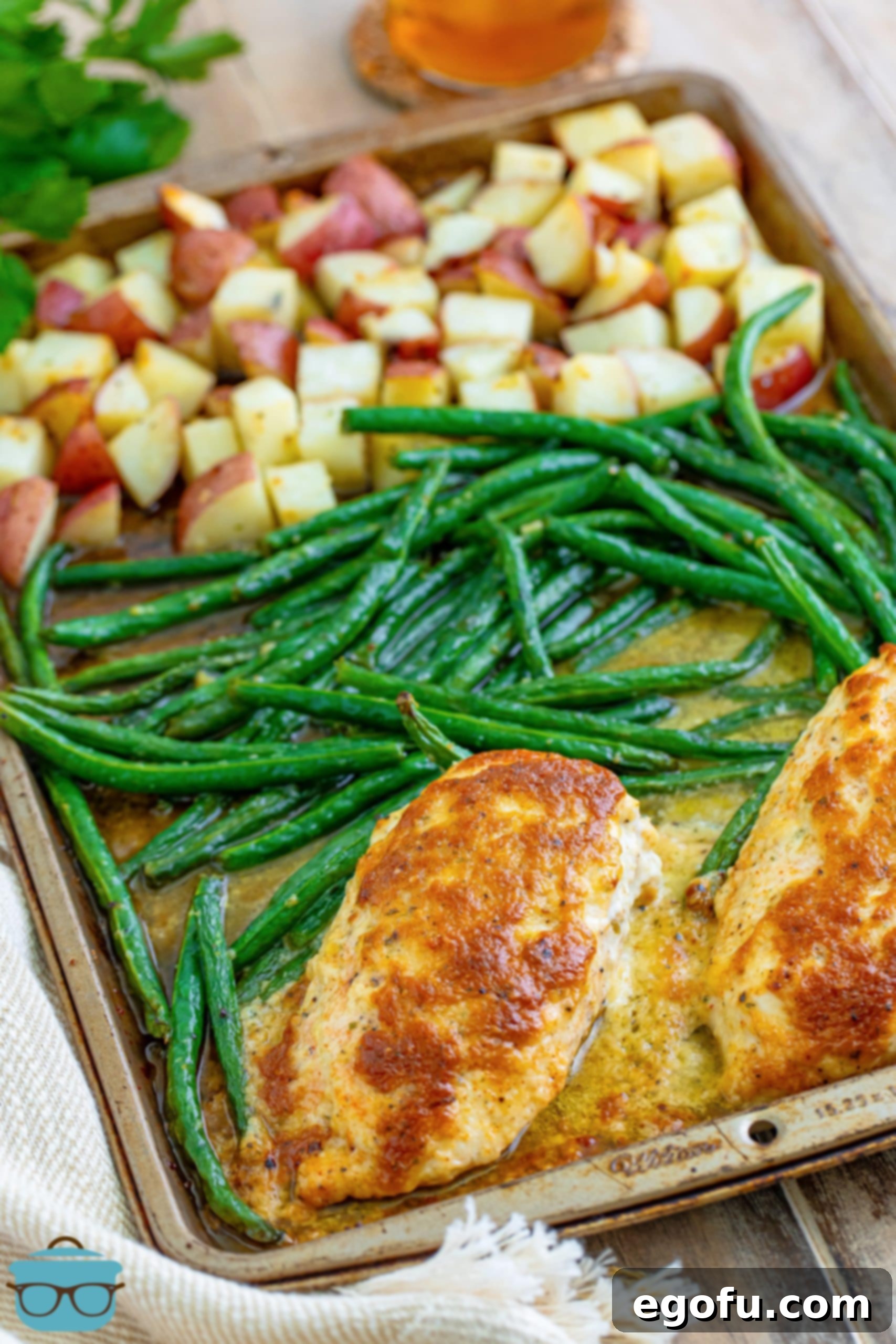 One-Pan Garlic Parmesan Chicken Dinner for Two 2 Garlic Parmesan Chicken on a sheet pan with green beans and red potatoes.