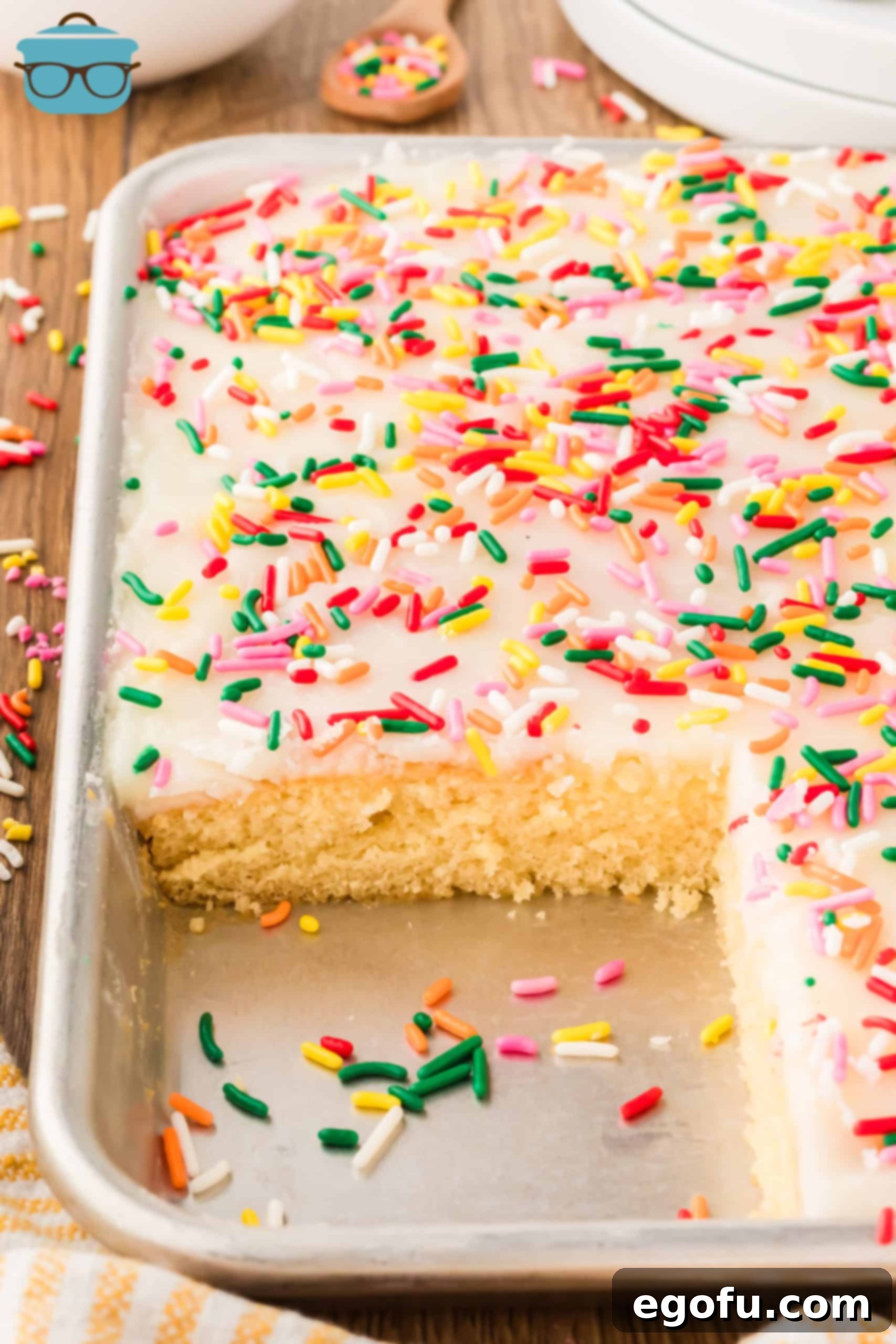 A large White Texas Sheet Cake in a sheet pan, with one slice missing and the remaining cake perfectly frosted.