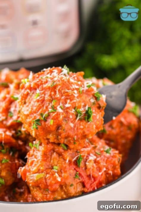 A close-up of a fork delicately holding a juicy Instant Pot Meatball, showcasing its tender texture and rich sauce.