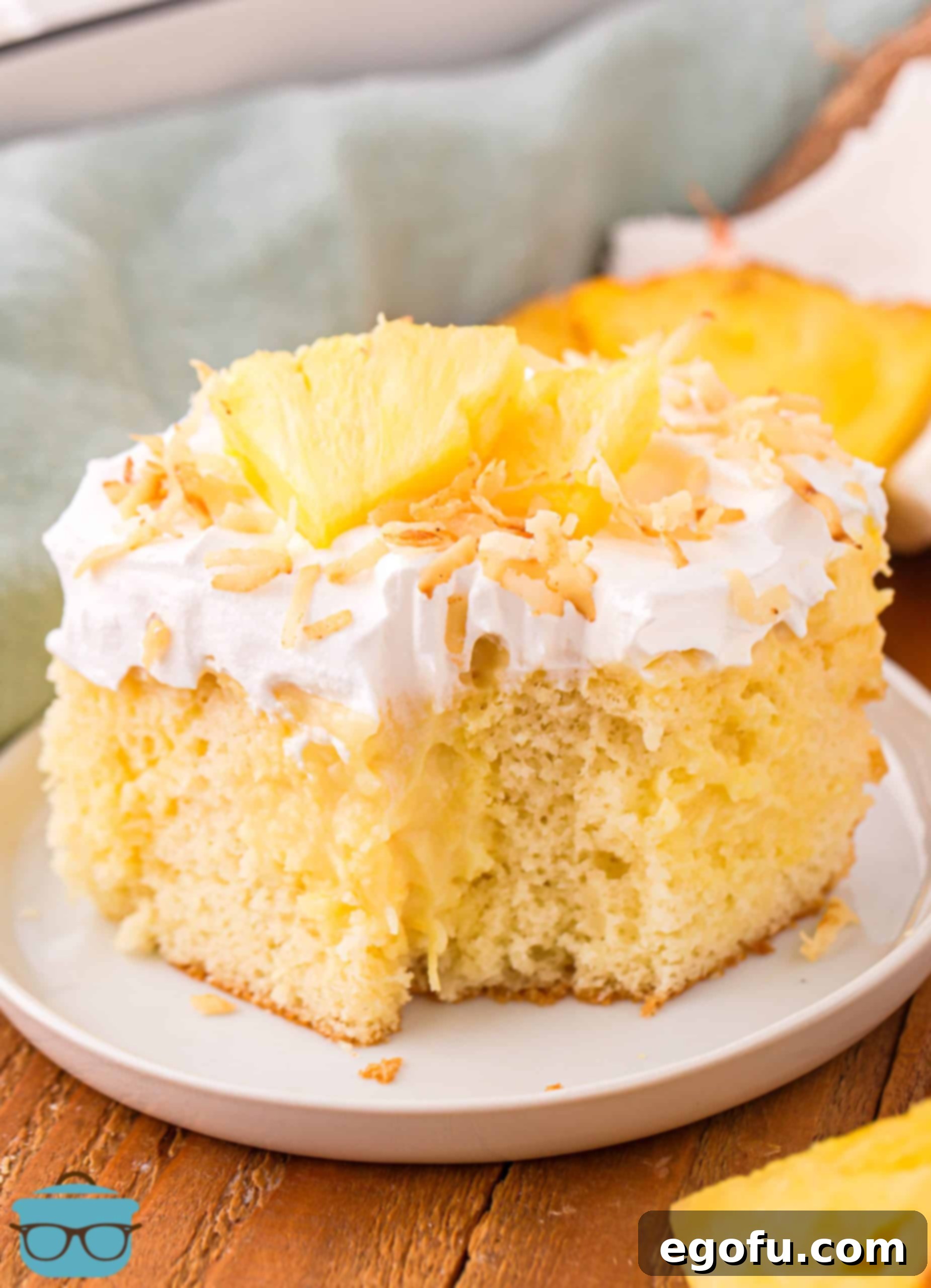 Sun-Kissed Hawaiian Poke Cake 2 A vibrant slice of Hawaiian Poke Cake with a bite taken out, showcasing the moist layers of cake and creamy filling.