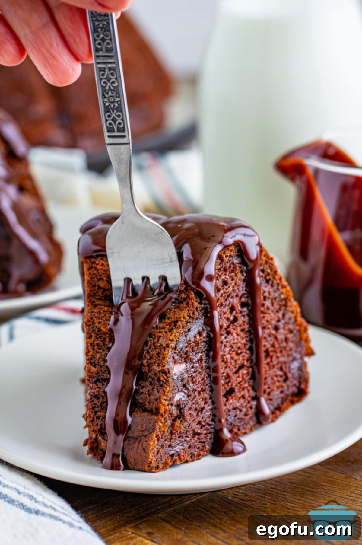 Velvet Chocolate Pudding Bundt 2 A beautiful slice of Chocolate Pudding Bundt Cake with a fork, ready for a bite.