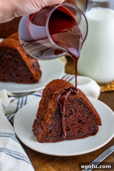Velvet Chocolate Pudding Bundt 18 Pouring chocolate sauce on a slice of chocolate cake.