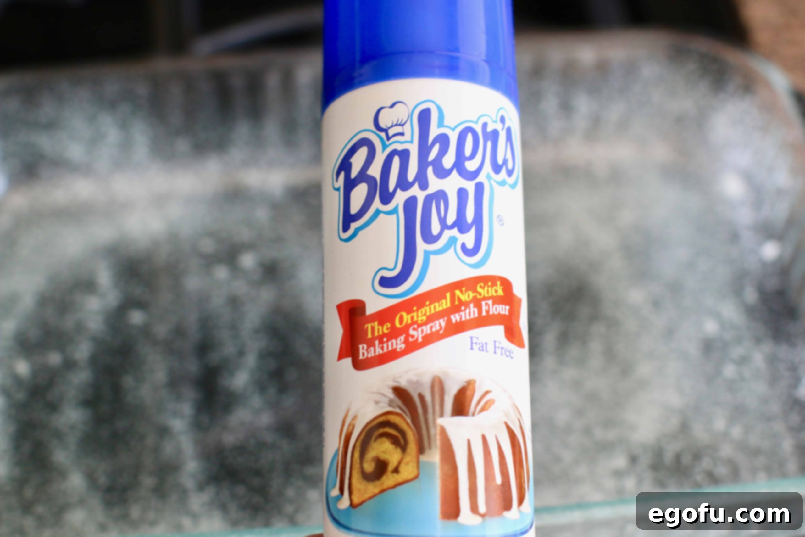 Velvet Chocolate Pudding Bundt 3 Detail shot of spraying a bundt cake pan with nonstick baking spray, emphasizing thorough coating.
