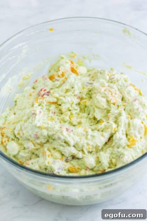 Whipped topping being stirred into Tropical Watergate Salad.