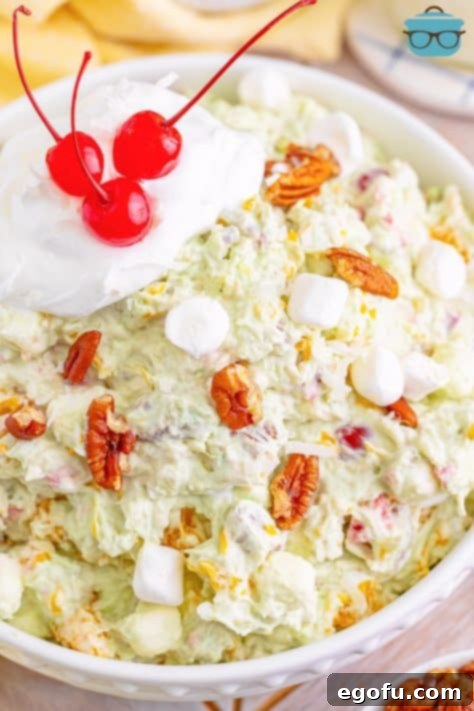 A bowl of Tropical Watergate Salad with fluff and cherries.
