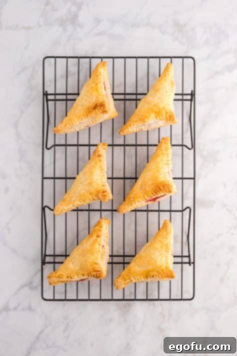 Cherry turnovers cooling on a wire rack after being removed from the oven.