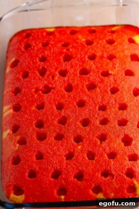 Raspberry jello poured over a cake with holes.