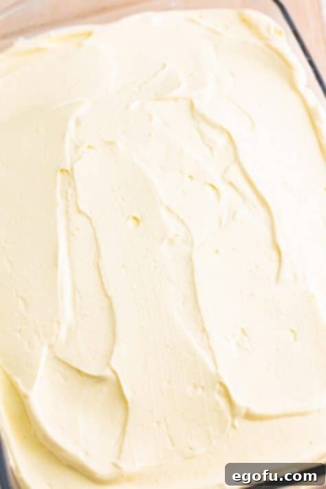 Frosting spread over a white cake with raspberry flavors.