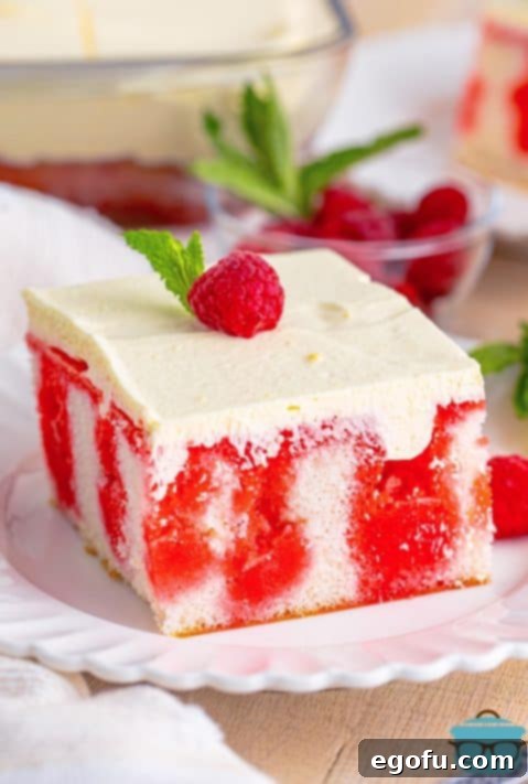 A slice of Raspberry Poke Cake with a raspberry on top.
