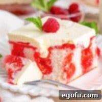 A slice of Raspberry Poke Cake with a fork holding a bite.
