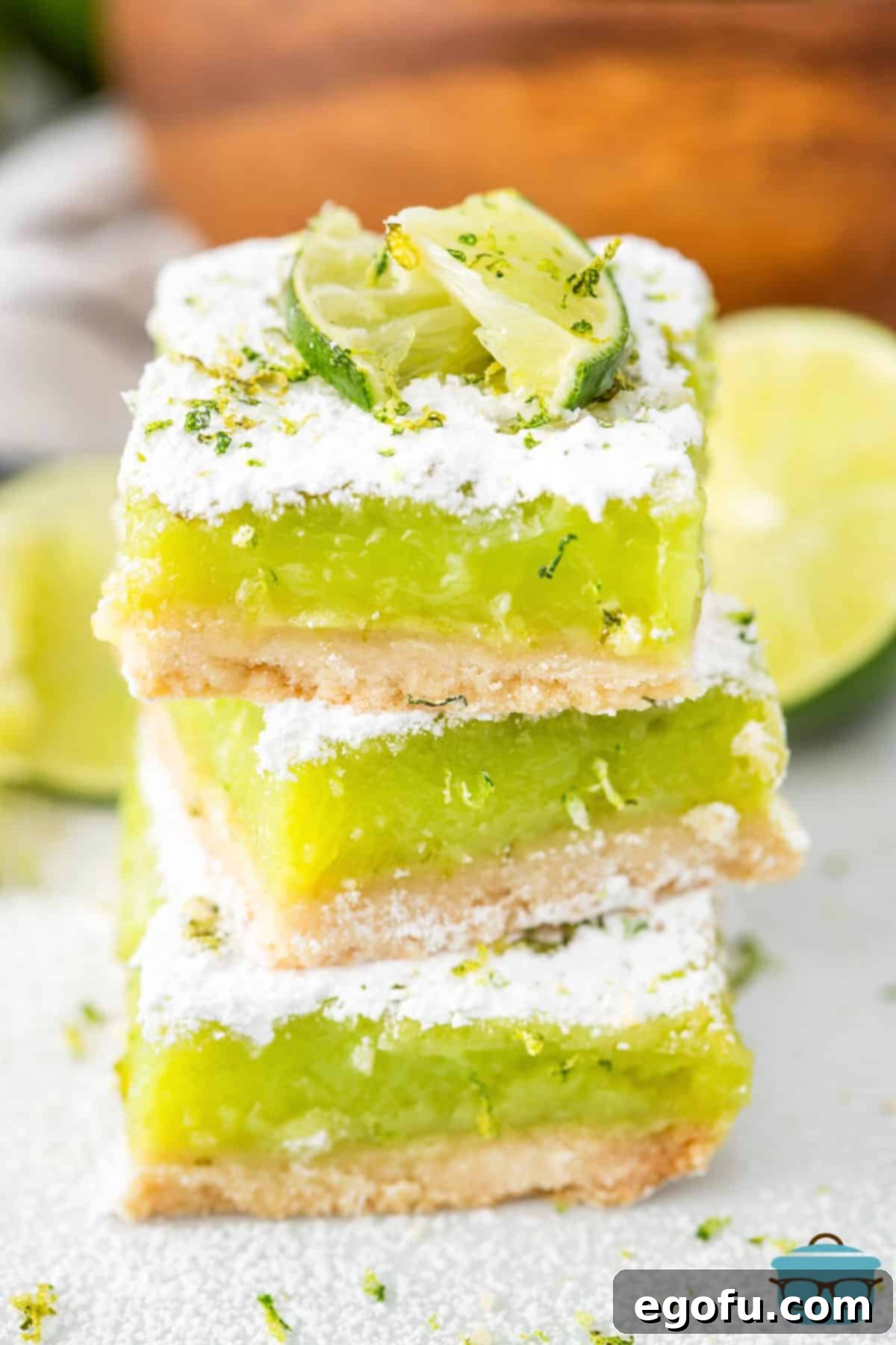A stack of perfectly cut Lime Bars, garnished with fresh lime slices, ready to be enjoyed.