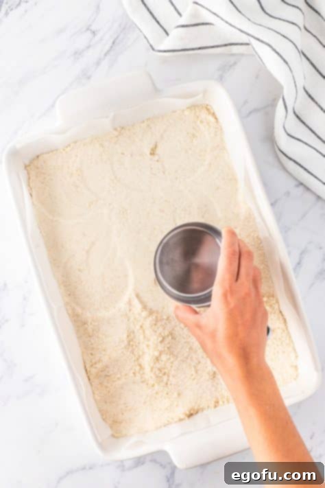 using a measuring cup to press crust into baking dish.