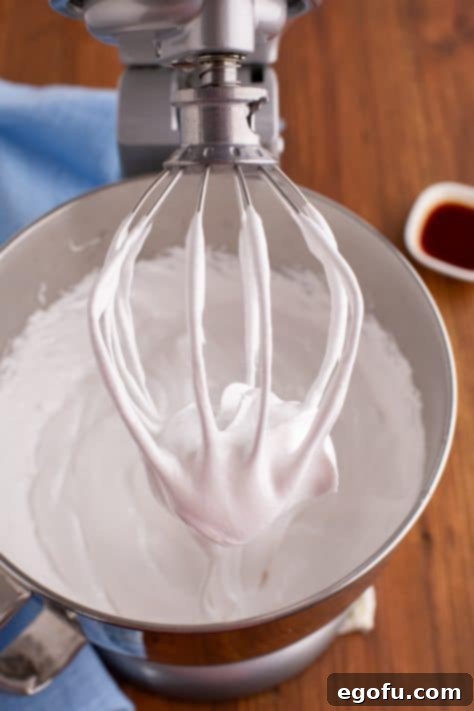 The whisk of a stand mixer with marshmallow filling dripping from it.