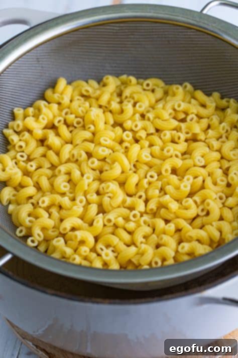 Cooked elbow macaroni in a strainer, ready to be returned to the pot.