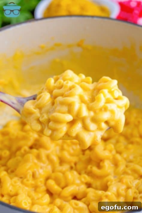 A pot of homemade KFC Mac and Cheese with a scoop on a spoon, illustrating the smooth, melted cheese sauce.