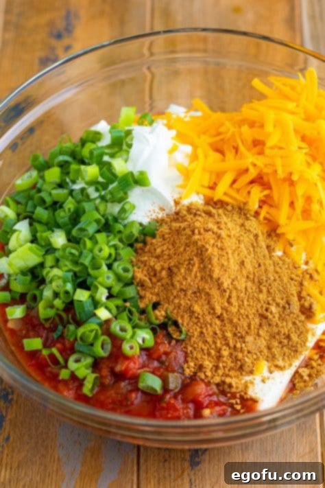Stars and Stripes Celebration Dip 12 A mixing bowl with cream cheese, salsa, sour cream, cheddar, green onions, and taco seasoning.