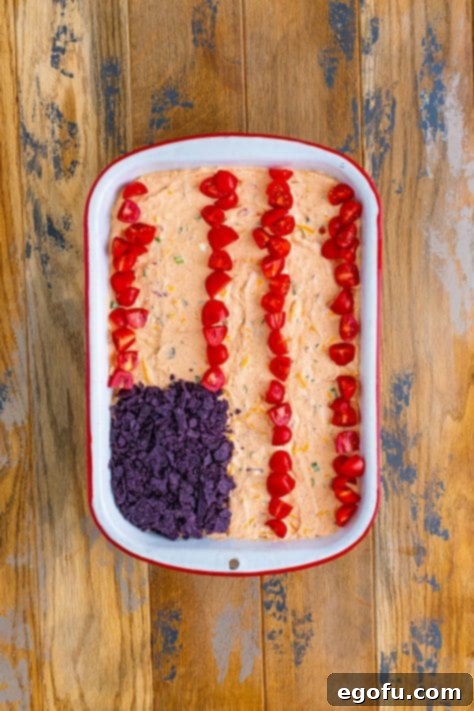 Stars and Stripes Celebration Dip 18 A baking dish with taco dip and rows of tomatoes and a rectangle of chips.