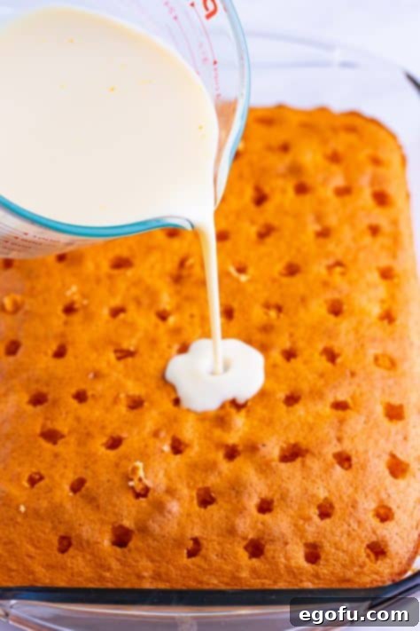 The sweetened condensed milk mixture being poured over the cake.