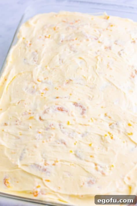 Orange whipped topping spread on top of orange cake.