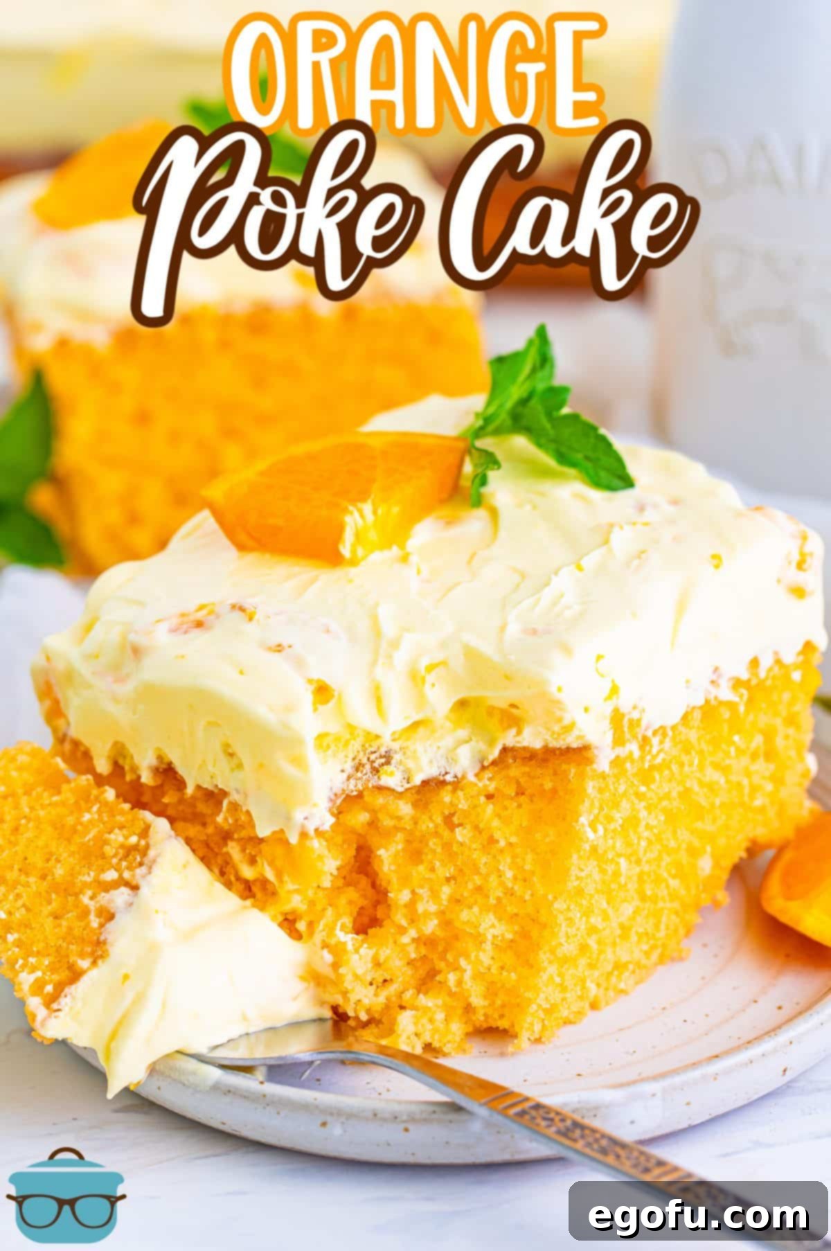 A delectable slice of Orange Poke Cake with a bite taken out, resting on a fork.