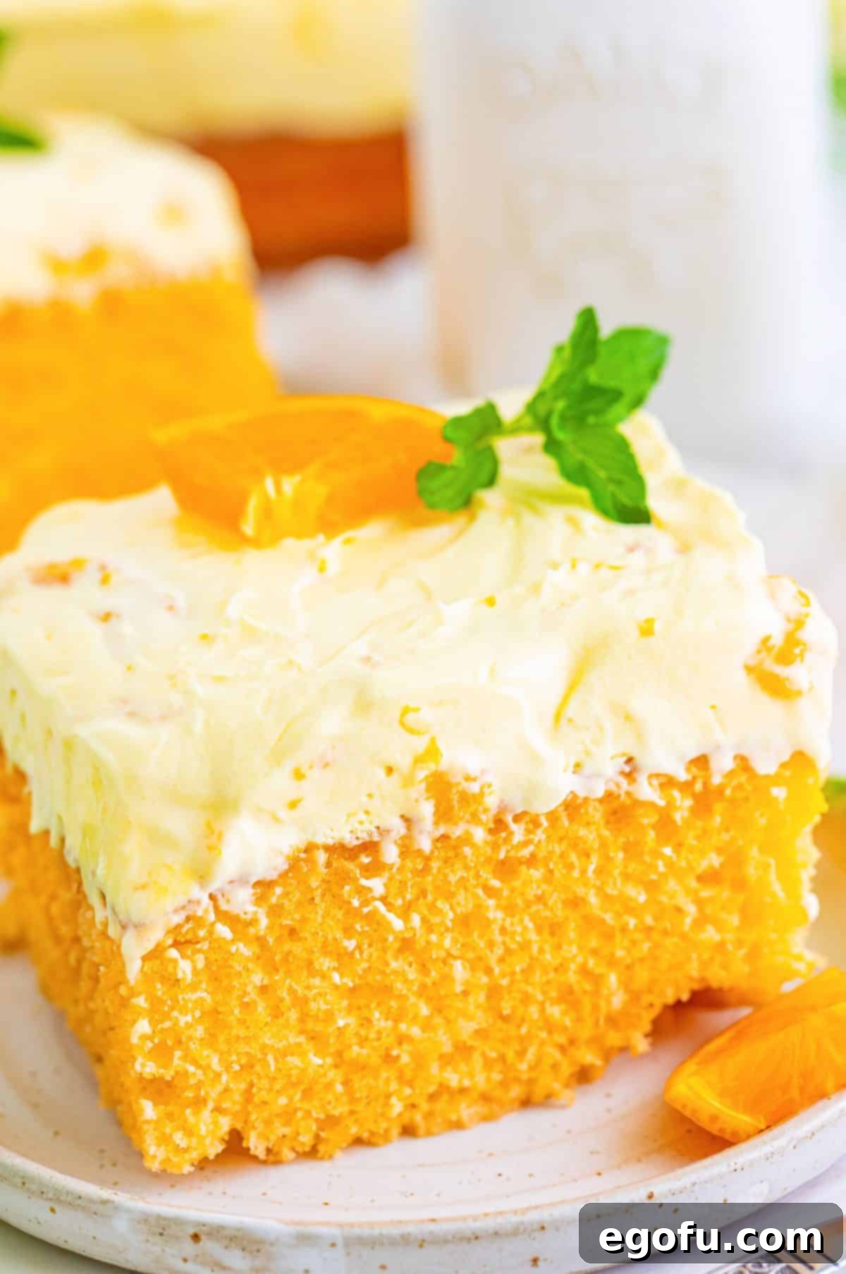 A generously sized piece of Homemade Orange Poke Cake displayed on a white dessert plate, ready to be enjoyed.