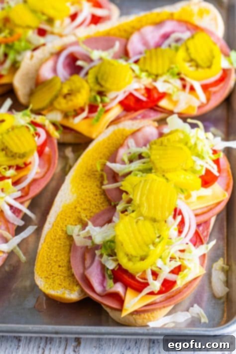 A sub roll with mustard, salami, bologna, ham, cheese, tomatoes, lettuce, onion, banana peppers, and pickles.