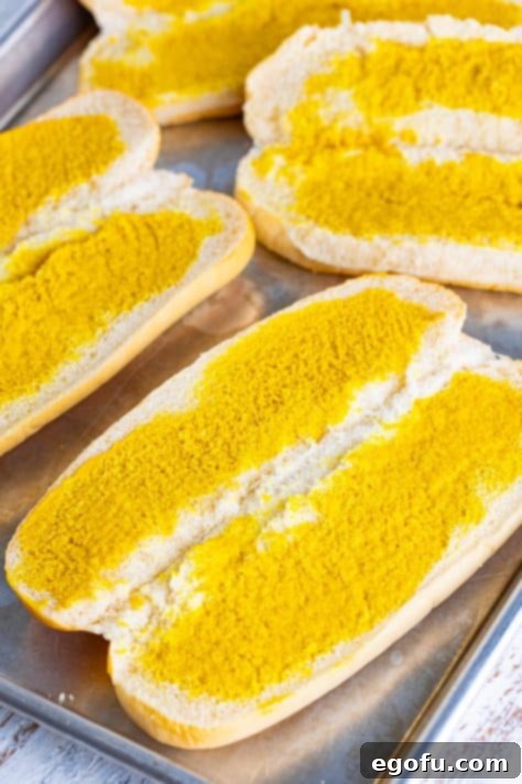 Open sub rolls with mustard on them.