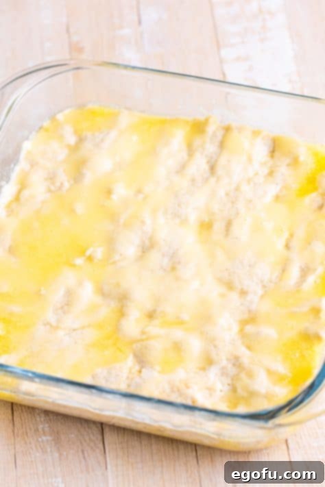 Golden Butter Soaked Cinnamon Sugar Biscuits 13 Butter on top of Biscuit dough in a baking dish.