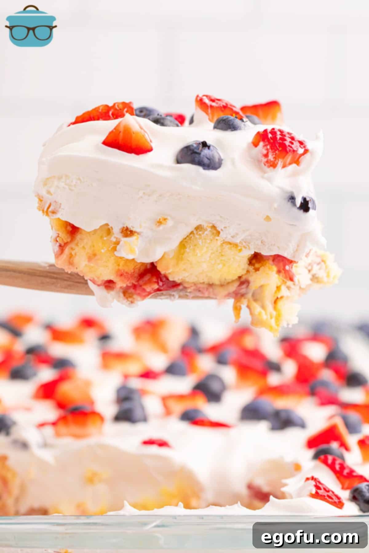 A serving utensil holding a slice of Patriotic No Bake Dessert, showcasing its red, white, and blue layers.