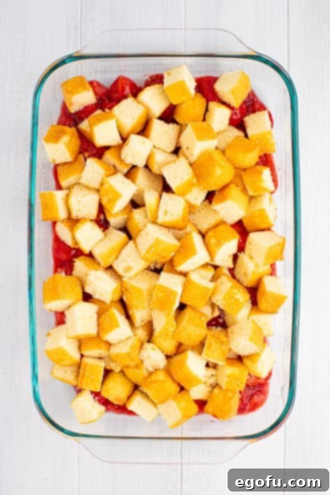 Strawberry pie filling and diced up pound cake in a baking dish.
