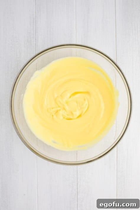 Vanilla pudding, sour cream, milk, and Cool Whip mixed together in a bowl.